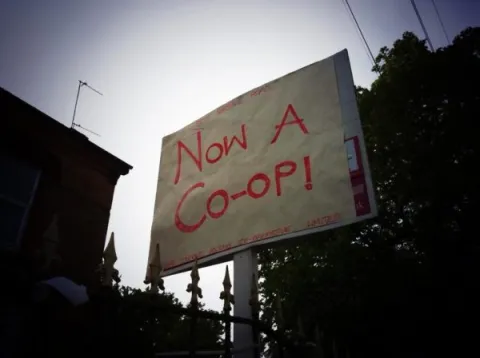 Sign outside building displaying message "Now a Co-op!"